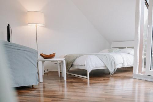 ein weißes Schlafzimmer mit einem Bett und einem Tisch in der Unterkunft Appartement Residenz Panorama - Einzigartiges Loft im Herzen von Würzburg mit 2 Balkonen und Panorama-Aussicht! in Würzburg