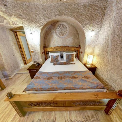 a bedroom with a bed in a stone wall at Roma Cave Suite in Goreme