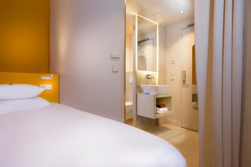 um quarto com uma cama branca e uma casa de banho em Hotel Andréa em Paris