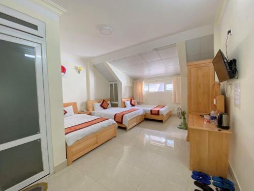 een hotelkamer met 2 bedden en een televisie bij Khách sạn Hải Hoa Đà Lạt in Da Lat