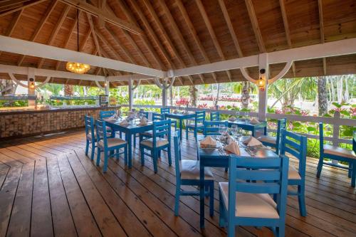 un restaurant avec des tables et des chaises bleues sur une terrasse en bois dans l'établissement Viva V Samana by Wyndham, A Trademark Adults All Inclusive, à Las Terrenas
