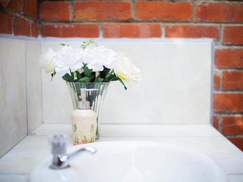 a vase filled with white flowers sitting on a sink at Water's Edge in Sedgefield