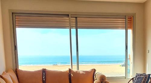 a living room with a large window with a view of the beach at Appartement pied dans l'eau in Imi Ouaddar