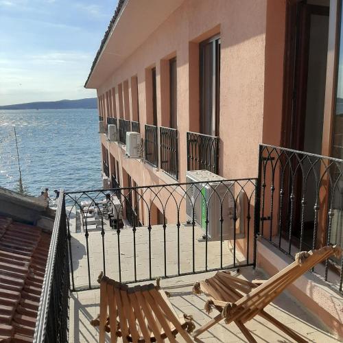 a couple of chairs on a balcony next to the water at CasaLyma Ayvalık in Ayvalık