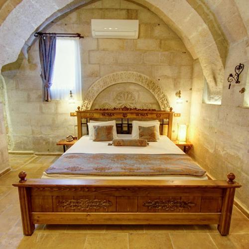 a bedroom with a large bed in a stone wall at Roma Cave Suite in Goreme