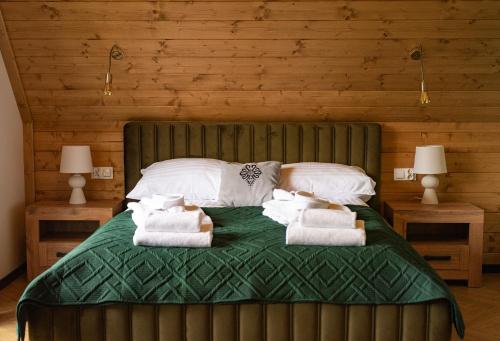 Un dormitorio con una cama verde con toallas. en Dom z widokiem na góry i prywatnym jacuzzi w Zębie, en Ząb