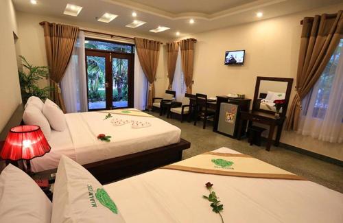 Saigon Emerald Beach Resort في موي ني: غرفة فندقية بسريرين ومكتب وتلفزيون