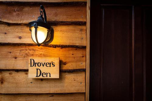 a light hanging on a wall with a sign that says flowers den at Black Sheep Hotels Cabins in Spean Bridge