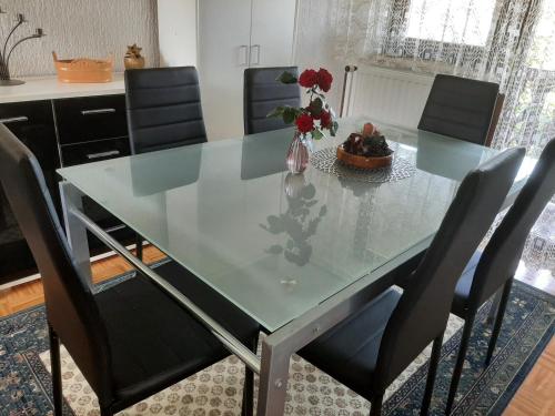 une table à manger en verre avec des chaises et un vase de fleurs dans l'établissement Počitniška hiška v Dolini miru, à Bogojina