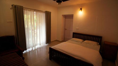 a bedroom with a bed and a large window at Thondiyar Estate Bungalow by LexStays in Thekkady