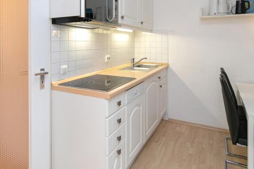 eine Küche mit weißen Schränken und einem Waschbecken in der Unterkunft Berolina Wohnung 805 Traum Ostseeblick in Dahme