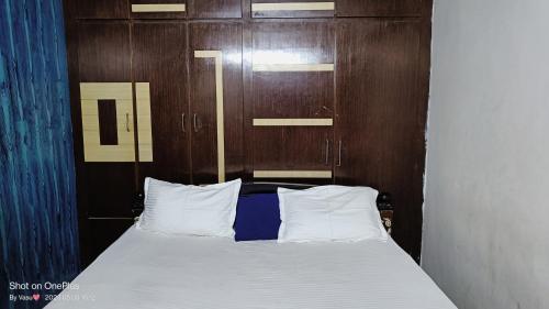 a bed with a wooden head board and white pillows at gratifiedhomestay in Visakhapatnam