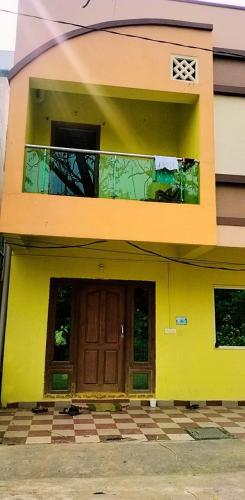 a yellow house with a door and a balcony at gratifiedhomestay in Visakhapatnam