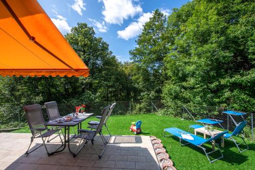 eine Terrasse mit einem Tisch, Stühlen und einem orangenen Sonnenschirm in der Unterkunft Ca' Mia Panoramica - Happy Rentals in Lugano