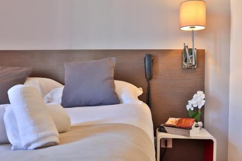 a hotel room with a bed and a lamp and flowers at Hotel & Restaurant Perla Riviera in Villeneuve-Loubet