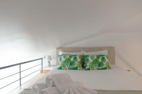 - une chambre blanche avec un lit et des oreillers verts dans l'établissement Antiga adega, à Óbidos