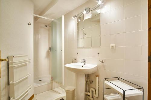 a white bathroom with a sink and a shower at Le Vernon in Chamrousse
