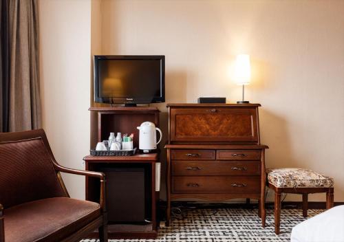 a hotel room with a bed and a dresser and a television at Kanazawa New Grand Hotel Prestige in Kanazawa
