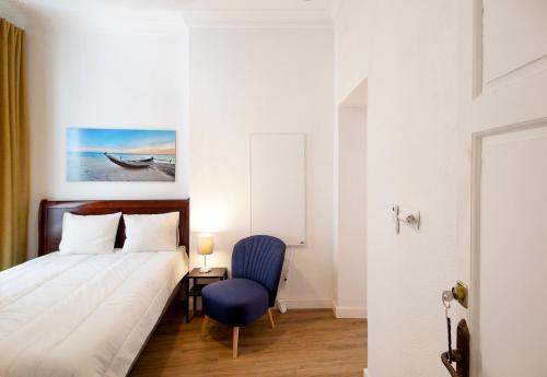 a bedroom with a bed and a blue chair at PALACIO DON CARLOS in Jerez de la Frontera