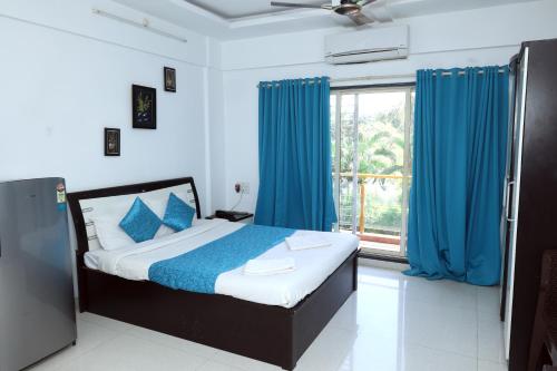 1 dormitorio con 1 cama con cortinas azules y ventana en Nilaya Nest Away, en Alibaug