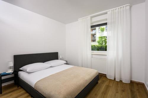 - une chambre blanche avec un lit et une fenêtre dans l'établissement Native Apartments Poznańska 7, à Cracovie