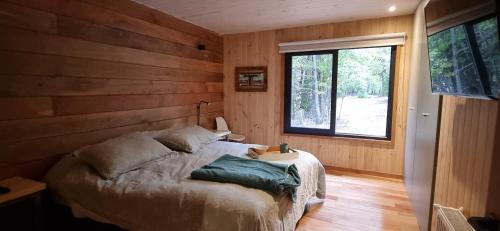a bedroom with a bed with a wooden wall at Refugio PIREN, Corralco, Hot Tub y nieve in Curacautín