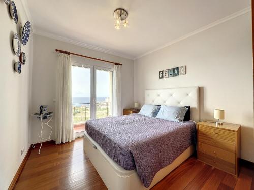 a bedroom with a bed and a large window at Reis Magos View in Caniço