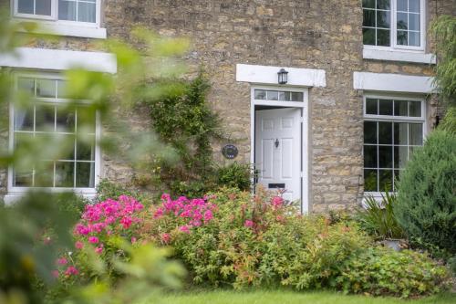 a brick house with a white door and flowers at Church Farm in Wilton