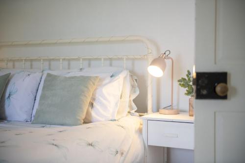 a white bed with pillows and a lamp on a night stand at Church Farm in Wilton