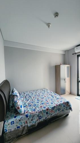 a bedroom with a bed with a floral comforter at Palam Mansion at Apartment One Residence in Batam Center