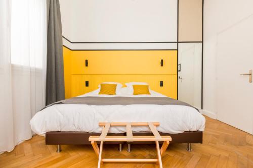 - une chambre avec un grand lit et une tête de lit jaune dans l'établissement Au Chat Qui Dort Lille - Villa Gounod, à Lille