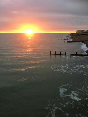 a sunset over a body of water with a pier at Ocean Breeze 5 minutes walk to the beach - Free Parking in Lancing