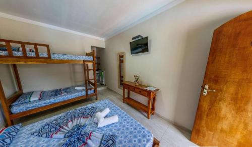 a bedroom with two bunk beds and a desk at Pousada da Árvore in Boicucanga