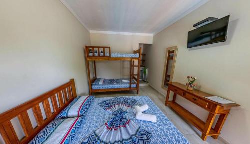 a bedroom with a bed and a tv on a wall at Pousada da Árvore in Boicucanga