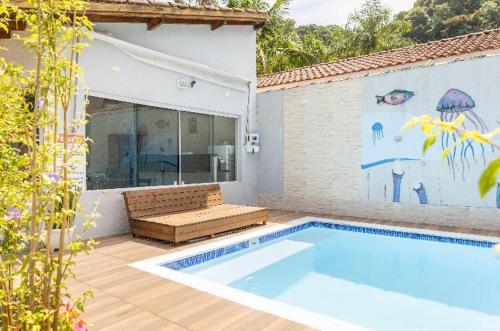 a swimming pool with a bench next to a house at Pousada da Árvore in Boicucanga