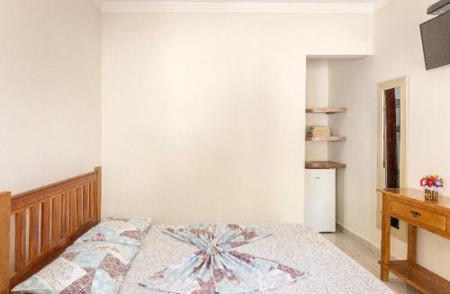 a bedroom with a bed with a blanket on it at Pousada da Árvore in Boicucanga