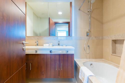 een badkamer met een wastafel, een bad en een spiegel bij LUXFolio Retreats - Amazing Full Burj Khalifa View in Dubai