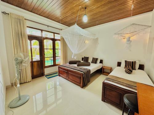 a bedroom with two beds and a desk and windows at GOLDEN CABIN ELLA in Ella