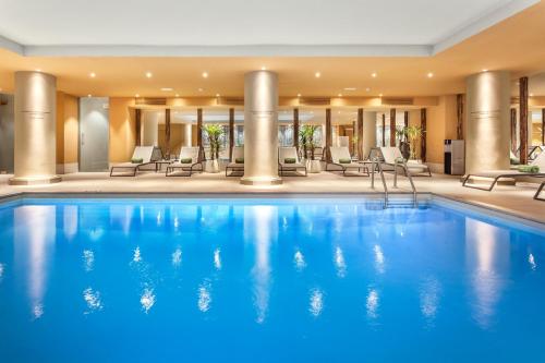 a large pool in a hotel with chairs and tables at Melia Madrid Princesa in Madrid