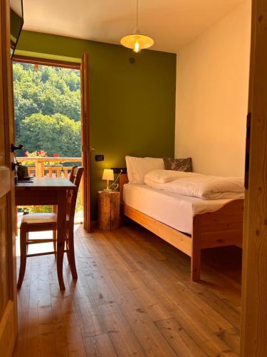 a bedroom with a bed and a table and a window at Agriturismo ValFraja in Cembra