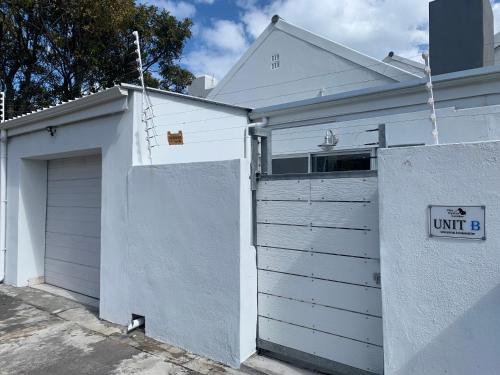 a white building with a garage with a sign on it at OysterCatcher Self-Catering Accommodation Strand in Cape Town