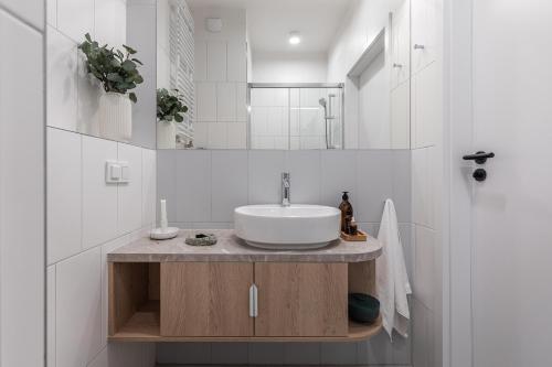 ein weißes Badezimmer mit einem Waschbecken und einem Spiegel in der Unterkunft Noli Mokotow in Warschau