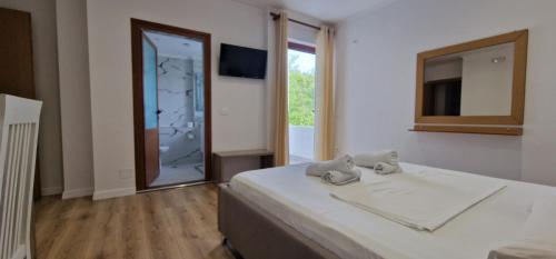 a bedroom with a bed and a mirror and a window at Kutal Parkinn Hotel in Përmet