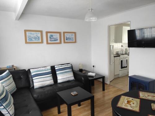 a living room with a black leather couch and a kitchen at 17 Breakaway Chalet in Great Yarmouth