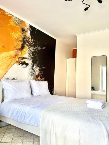 a bedroom with a white bed with a painting on the wall at PRIMA APARTMENTS in Satu Mare