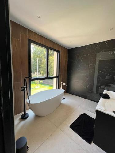 duża łazienka z wanną i oknem w obiekcie Villa haut standing avec piscine w mieście Gradignan