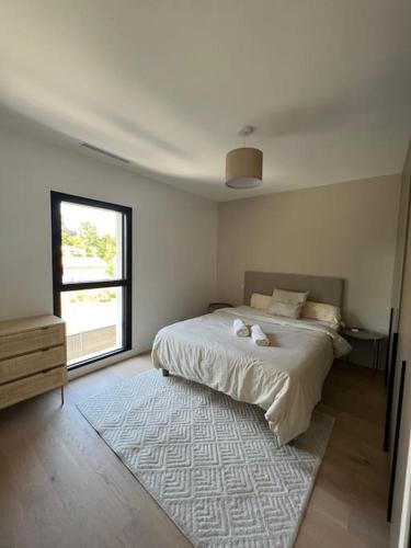 a white bedroom with a bed and a window at Villa haut standing avec piscine in Gradignan