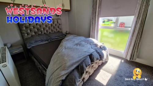 a bedroom with a bed in a room with a window at 3 Bedroom Caravan at Seal Bay Resort in Selsey
