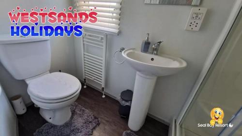 a bathroom with a toilet and a sink at 3 Bedroom Caravan at Seal Bay Resort in Selsey