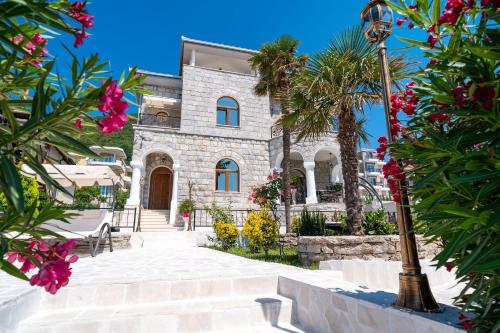 a stone house with palm trees in front of it at Villa Garden Beach in Bijela